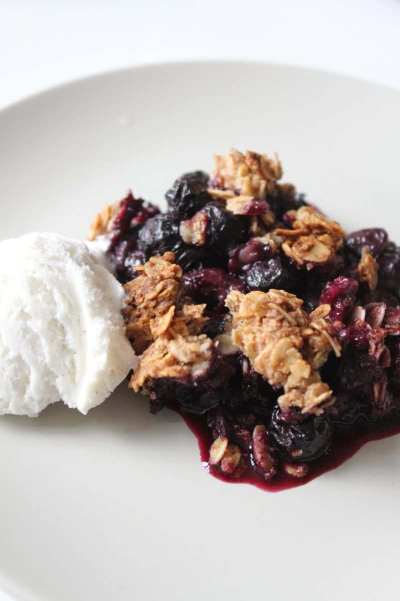 vegan blueberry crisp with a scoop of vanilla ice cream