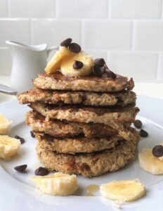 Stack of 6 vegan banana pancakes on a plate with a white backsplash in the background