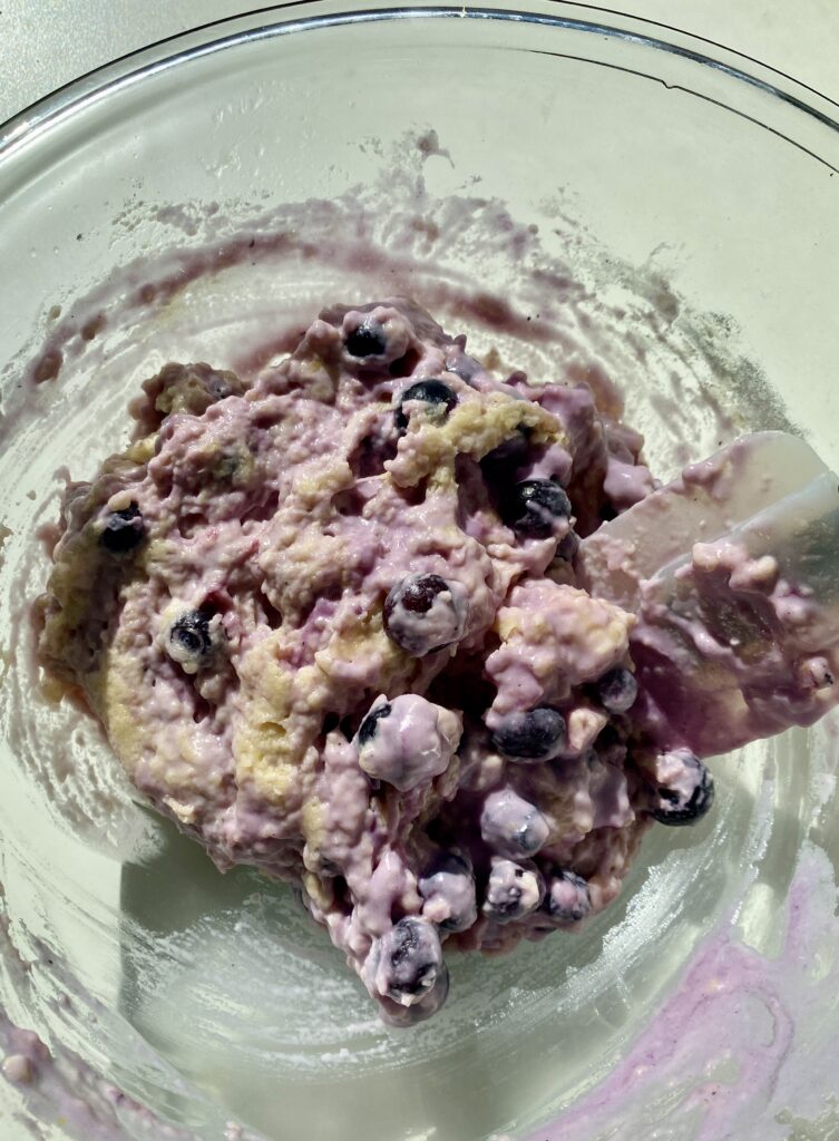 Batter for lemon blueberry muffins a gorgeous blue and purple color in a glass bowl