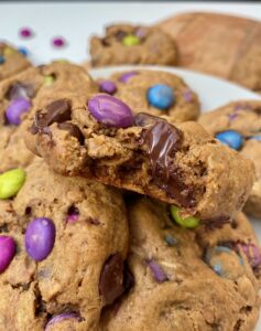 close up of some gluten free monster cookies. the one on top is bitten into and chocolate is oozing out of it