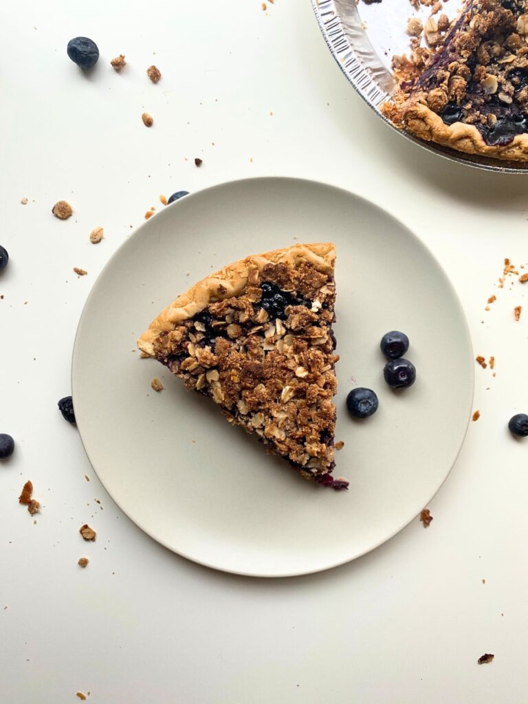 Slice of Blueberry Pie on a white plate from a birds eye view